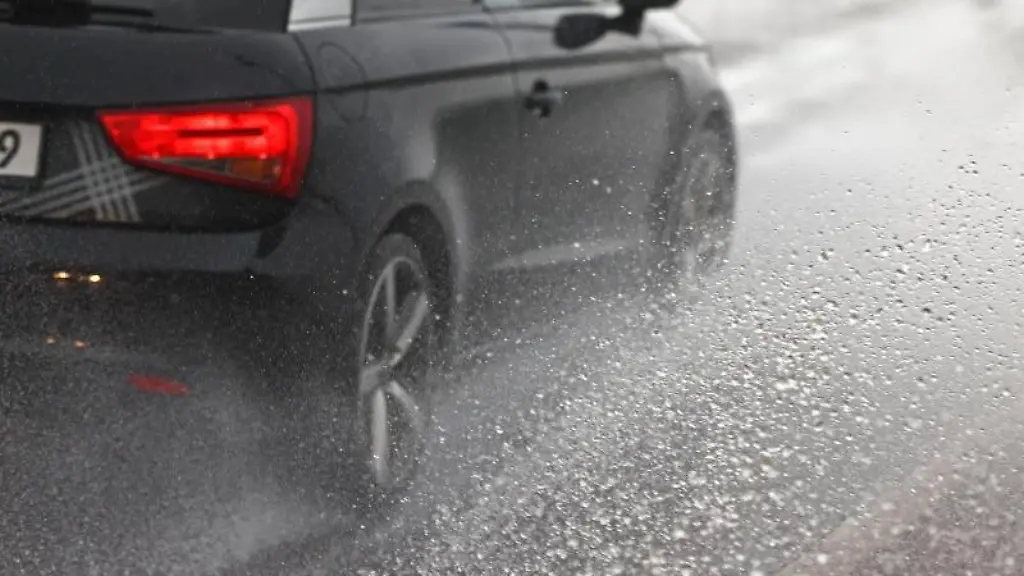 Ein-Auto-faehrt-im-Regen-durch-eine-Pfuetze