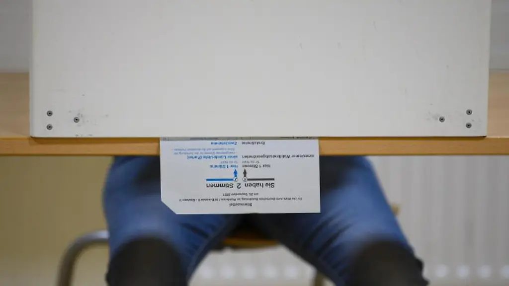 Ein-Waehlerin-sitzt-im-Wahllokal-mit-ihrem-Stimmzettel-in-der-Wahlkabine