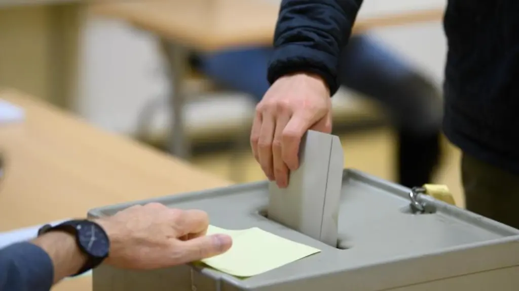 Ein-Waehler-wirft-bei-der-Stimmabgabe-zur-Bundestagswahl-im-Wahllokal-seinen-Stimmzettel-in-eine-Wahlurne