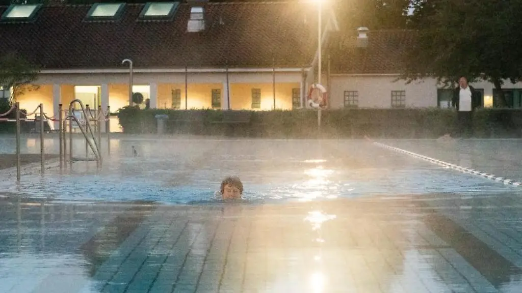 Eine-Frau-schwimmt-am-fruehen-Morgen-bei-Sonnenaufgang-im-Freibad-Grossburgwedel