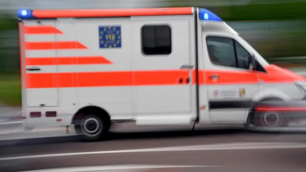 Ein-Krankenwagen-faehrt-mit-Blaulicht-auf-einer-Strasse