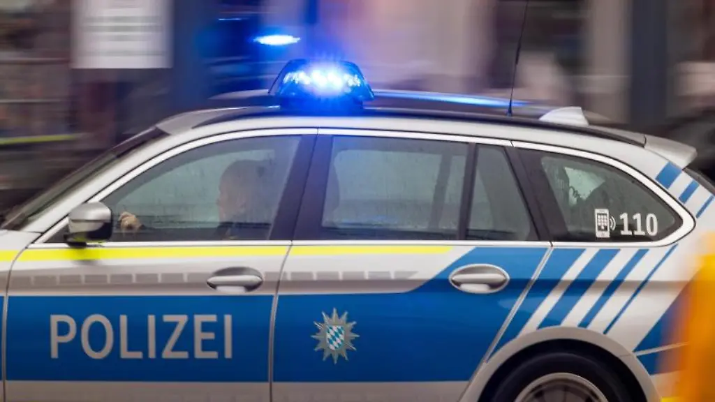 Ein-Fahrzeug-der-bayerischen-Polizei-faehrt-mit-Blaulicht-durch-die-Innenstadt