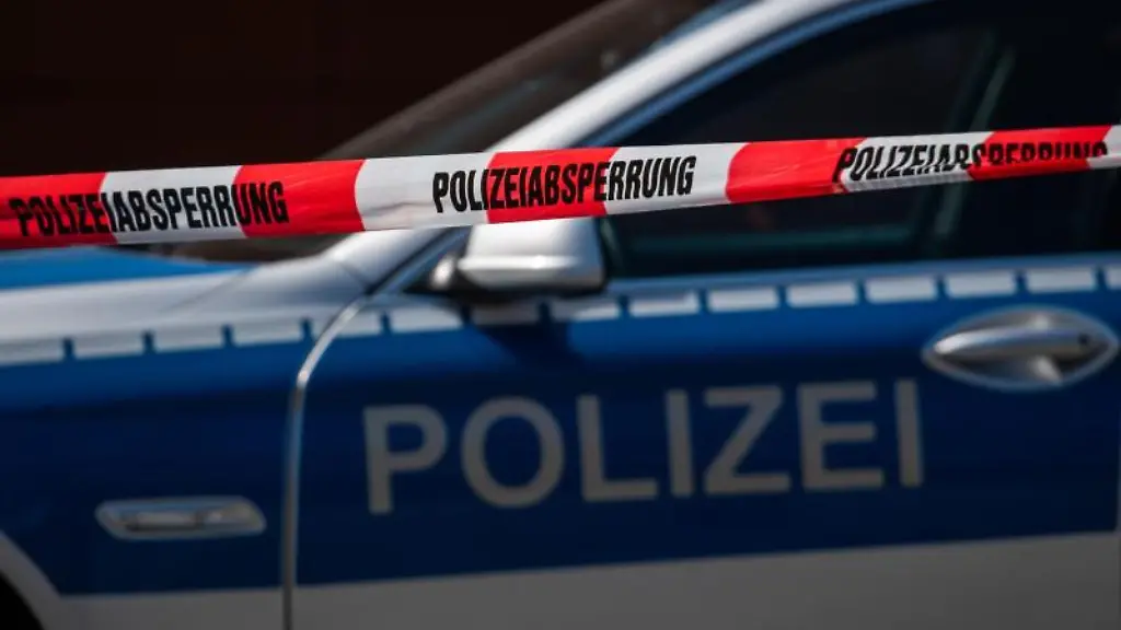 Ein-Polizeiauto-steht-hinter-einem-Absperrband-der-Polizei