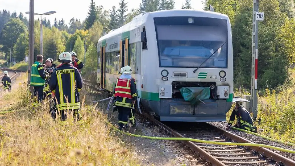 Einsatzkraefte-der-Polizei-und-Feuerwehr-stehen-nach-Loescharbeiten-an-einem-Zug-der-Vogtlandbahn