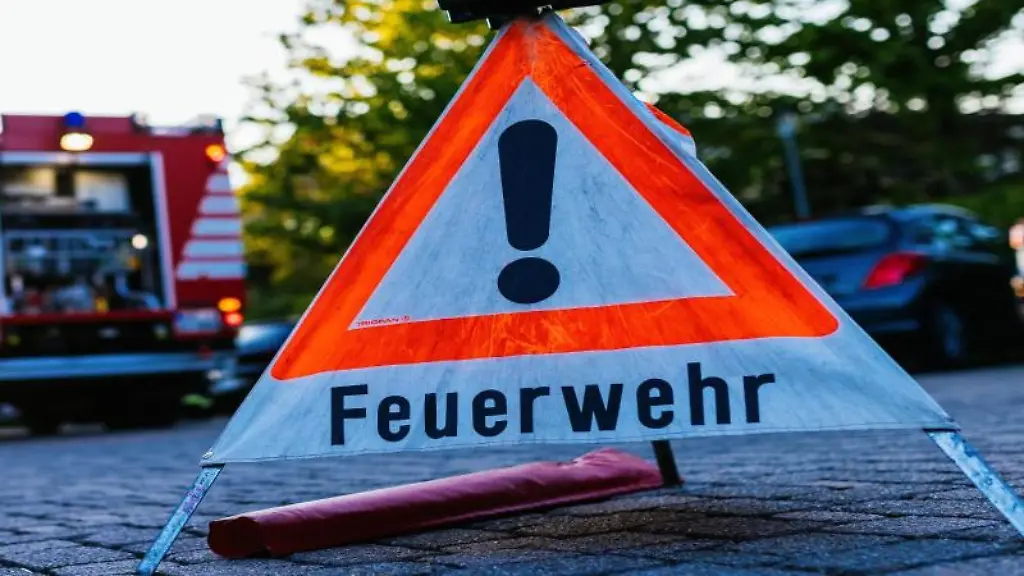 Ein-Warndreieick-mit-der-Aufschrift-Feuerwehr-steht-auf-dem-Hof-eines-Feuerwehrgeraetehauses