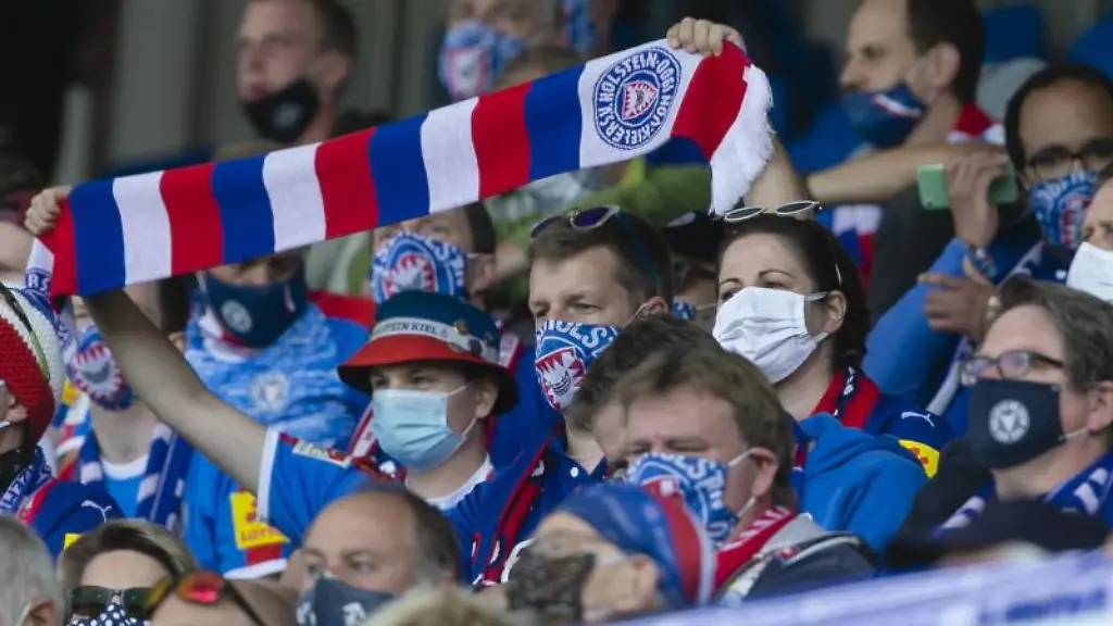 Fans-von-Holstein-Kiel-halten-ihre-Schals-in-die-Hoehe