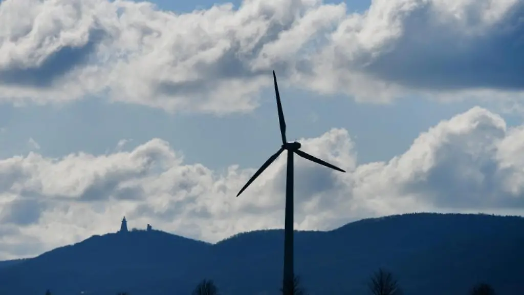 Ein-Auto-faehrt-neben-einem-Windrad-ueber-eine-Landstrasse