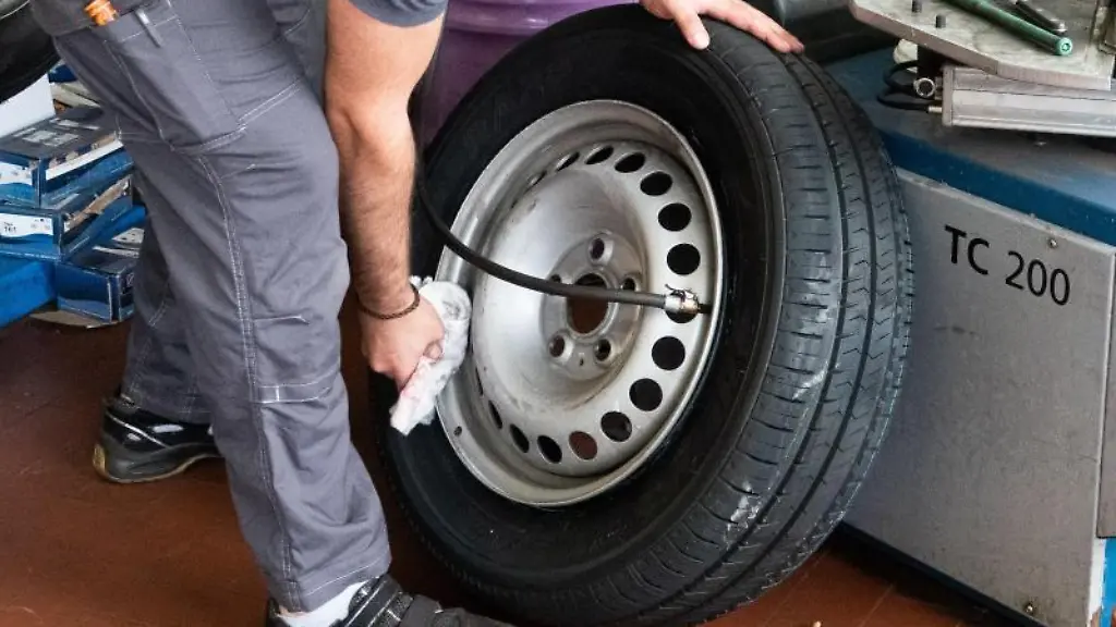 Ein-Auszubildender-zum-KfZ-Mechatroniker-pumpt-einen-Reifen-auf