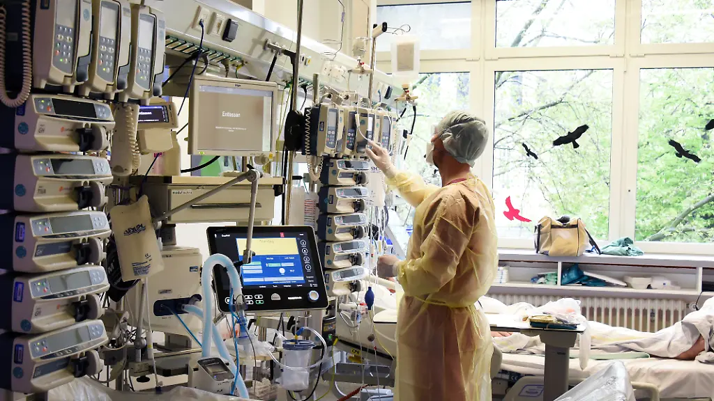 Ein-Krankenpfleger-ueberprueft-die-Geraete-am-Bett-eines-Intensiv-Patienten-Die-Bundesregierung-will-die-Zahl-der-hospitalisierten-Covid-19-Patienten-zum-neuen-Orientierungswert-zur-Bewertung-der-Pandemielage-machen