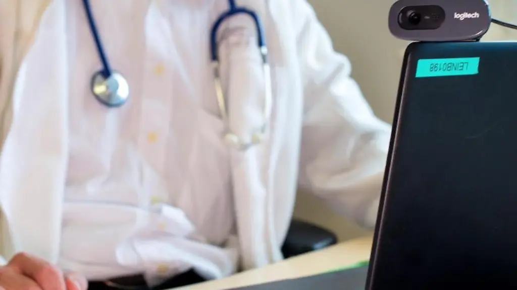 Ein-Hausarzt-sitzt-waehrend-einer-Videosprechstunde-in-seiner-Praxis-vor-einem-Laptop