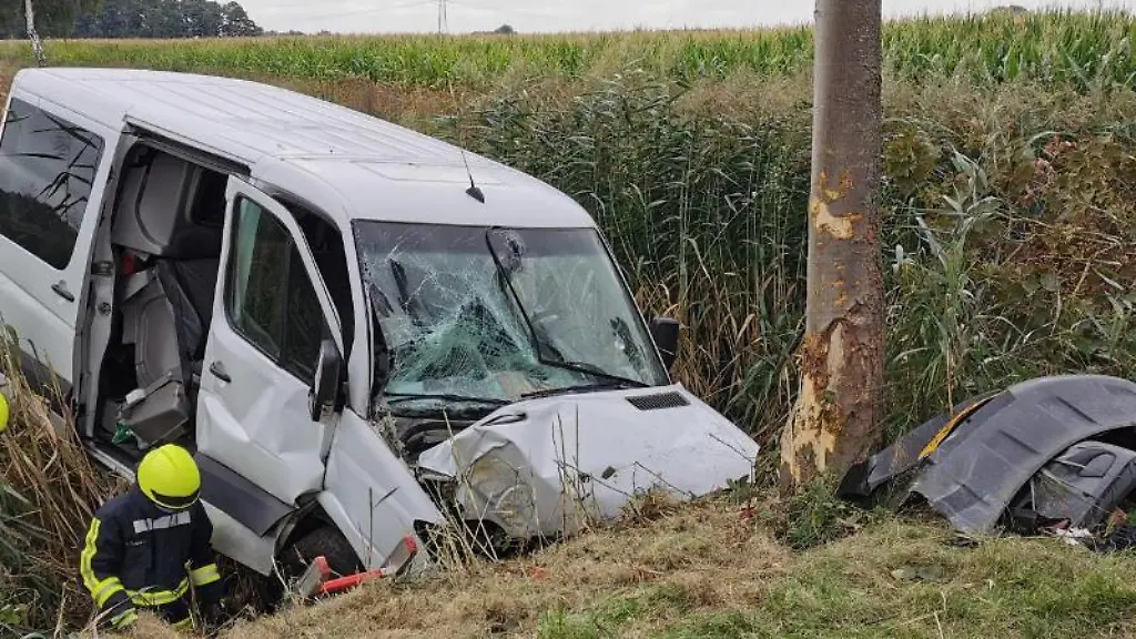 Rettungskraefte-stehen-am-Wrack-eines-Kleintransporters