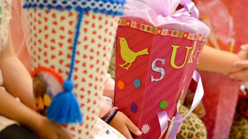 Erstklaessler-sitzen-mit-ihren-Ranzen-und-Zuckertueten