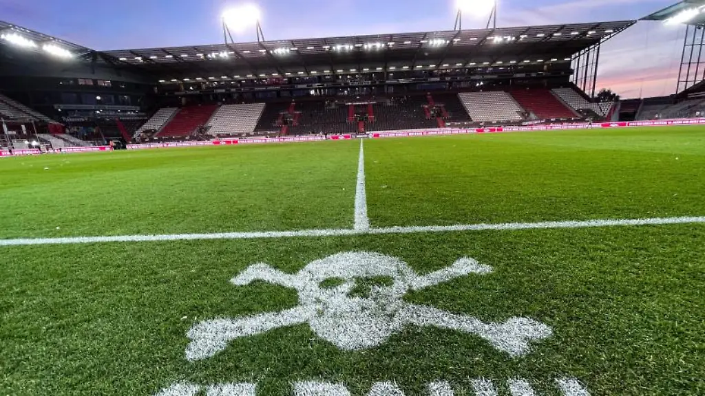 Das-Logo-von-St-Pauli-ist-an-der-Mittellinie-vor-den-Trainerbaenken-auf-den-Rasen-gesprueht