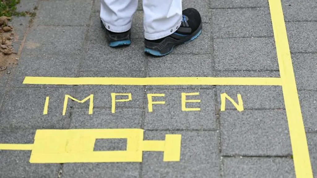 Ein-Mann-steht-an-einem-Covid-19-Impfcenter-hinter-der-Bodenaufschrift-Impfen