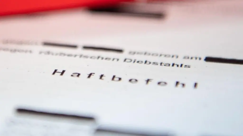 Eine-Abschrift-eines-Haftbefehls-liegt-mit-einem-Strafrecht-Buch-auf-dem-Tisch