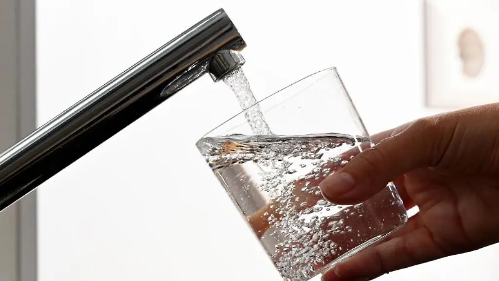 Eine-Hand-haelt-ein-Wasserglas-unter-einen-Wasserhahn