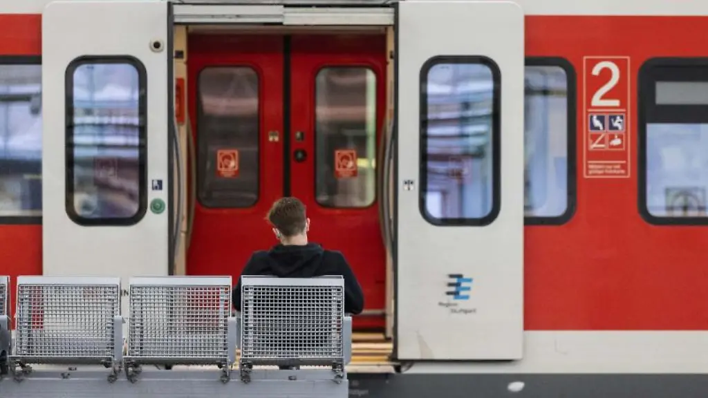 Ein-Mann-wartet-am-Gleis-auf-einer-Bank