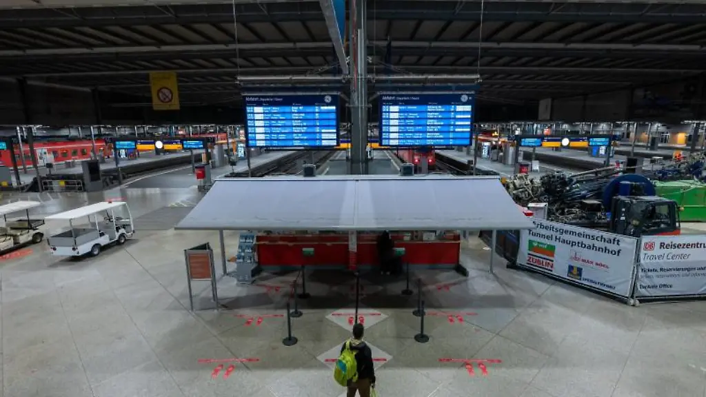 Ein-Passagier-steht-am-fruehen-Morgen-am-Muenchner-Hauptbahnhof-am-Infoschalter