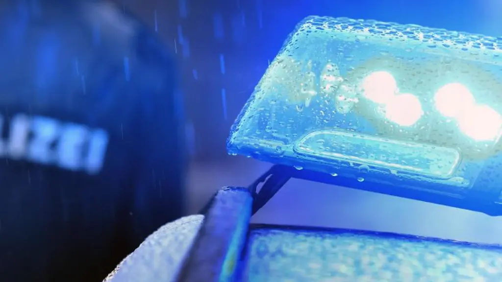 Ein-Polizist-steht-vor-einem-Streifenwagen-mit-Blaulicht