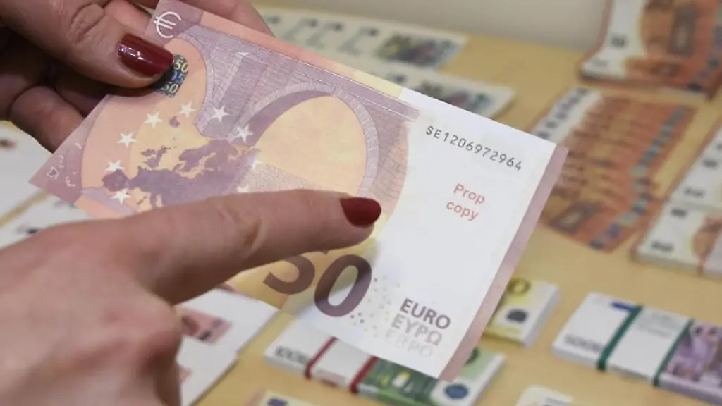 Eine-Frau-haelt-im-Landeskriminalamt-eine-gefaelschte-50-Euro-Banknote-in-einer-Hand-und-zeigt-darauf