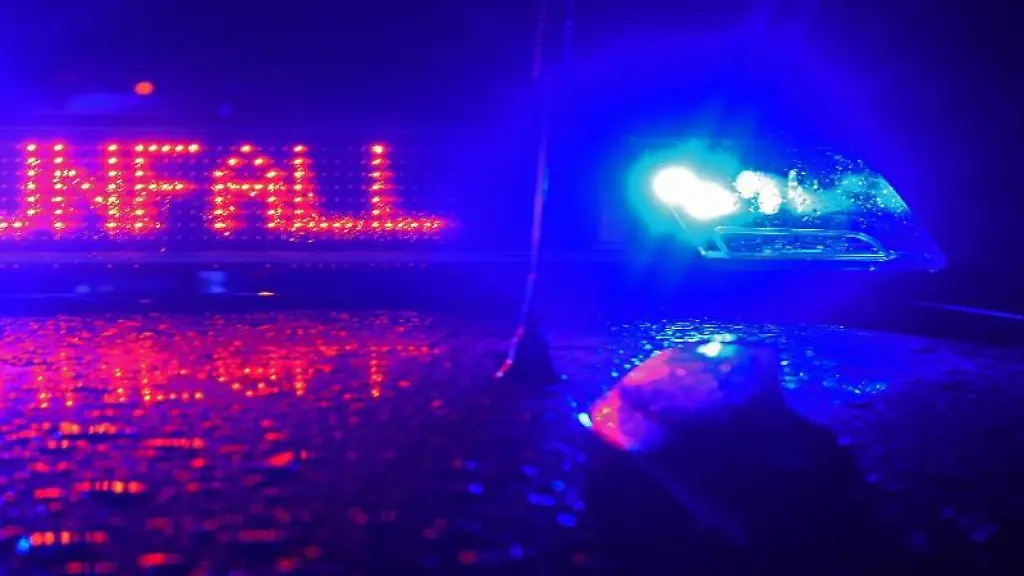 Waehrend-einer-Unfallaufnahme-spiegelt-sich-der-Schriftzug-Unfall-auf-dem-Dach-eines-Polizeiwagens