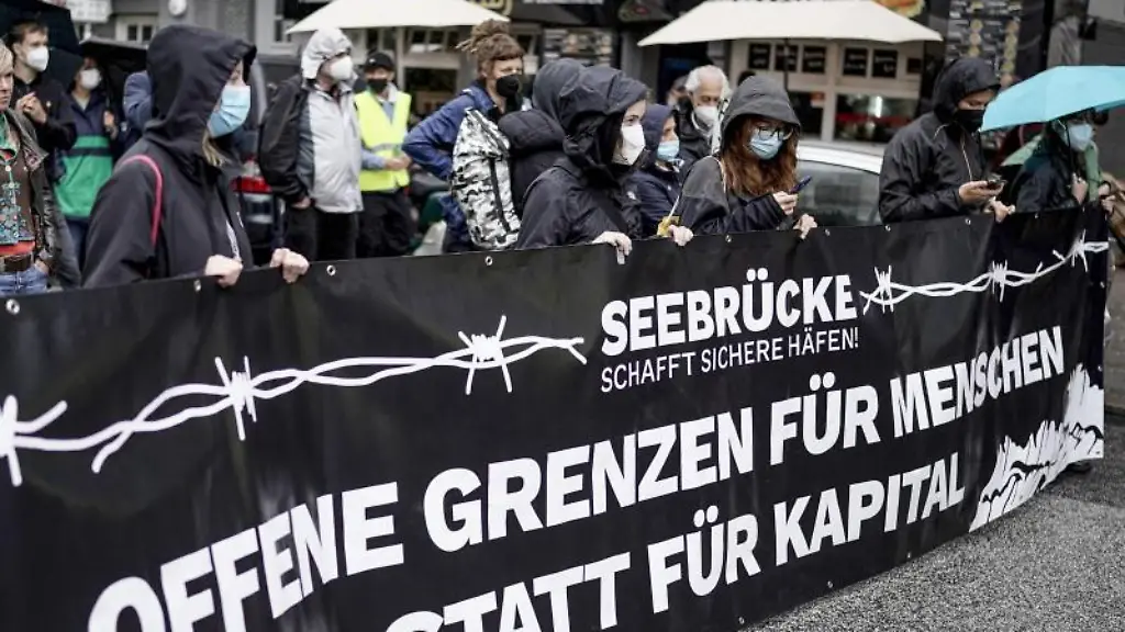 Teilnehmer-einer-Afghanistan-Solidaritaets-Demonstration-im-Hamburger-Stadtteil-St-Georg-tragen-ein-Banner-mit-der-Aufschrift-Offene-Grenzen-fuer-Menschen-statt-fuer-Kapital-vor-sich