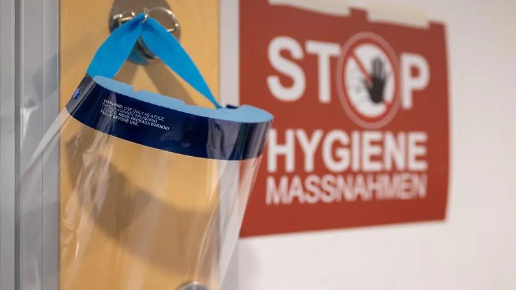Ein-Gesichtsschutz-haengt-neben-einem-Schild-mit-der-Aufschrift-Stop-Hygienemassnahmen