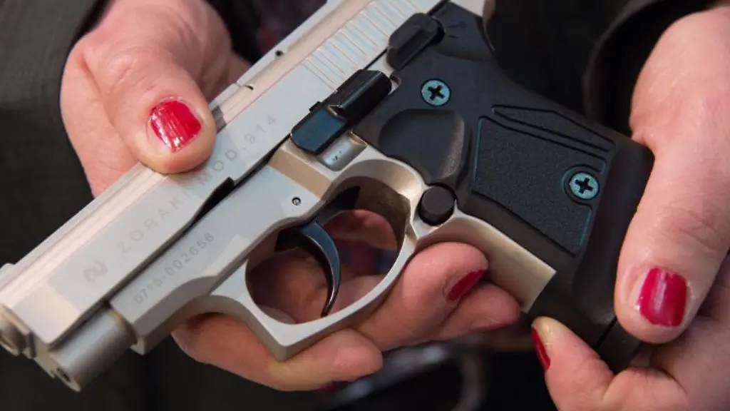 Eine-Frau-haelt-einem-Waffengeschaeft-eine-Schreckschusspistole-in-den-Haenden