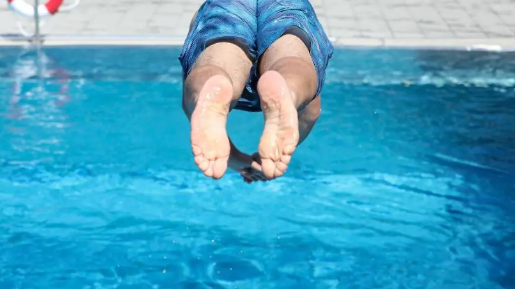 Ein-Mann-springt-von-einem-Sprungbrett-kopfueber-ins-Wasser