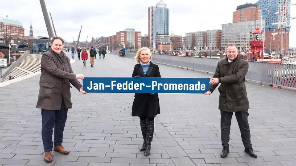 Carsten-Brosda-SPD-l-r-Hamburgs-Kultursenator-Marion-Fedder-Witwe-des-Schauspielers-Jan-Fedder-und-Andy-Grote-SPD-Innensenator-von-Hamburg-stehen-am-Hafen-und-halten-ein-Schild-mit-der-Aufschrift-Jan-Fedder-Promenade