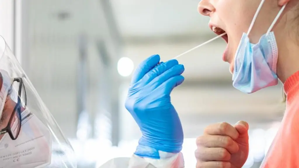 Ein-medizinischer-Mitarbeiter-entnimmt-einer-Frau-einen-Abstrich-fuer-einen-Corona-Test