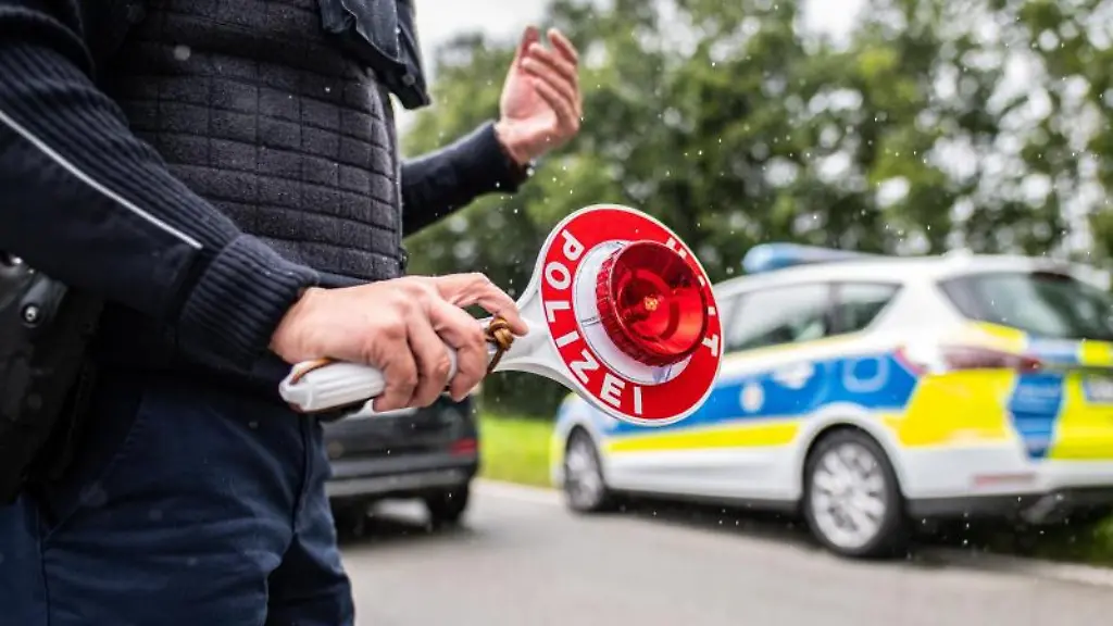 Eine-Polizistin-steht-mit-einer-Winkerkelle-in-der-Hand-auf-der-Strasse