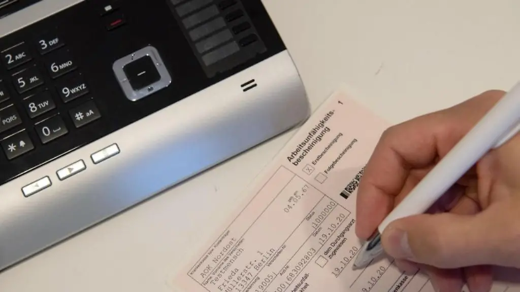 Ein-Mitarbeiter-einer-Arztpraxis-notiert-etwas-auf-einer-Arbeitsunfaehigkeitsbescheinigung