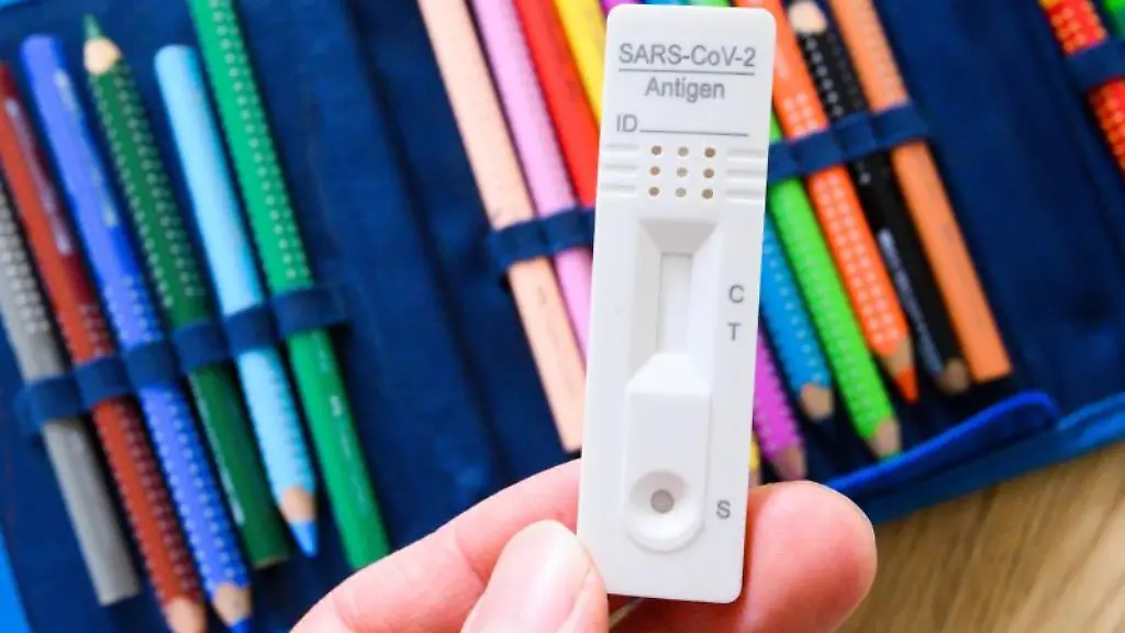 Ein-Corona-Selbsttest-wird-ueber-dem-Federmaeppchen-eines-Grundschuelers-gehalten