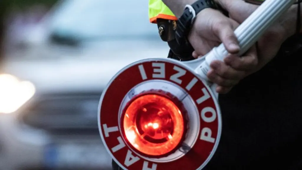 Ein-Polizist-haelt-an-einer-Kontrollstelle-eine-Winkerkelle-in-der-Hand