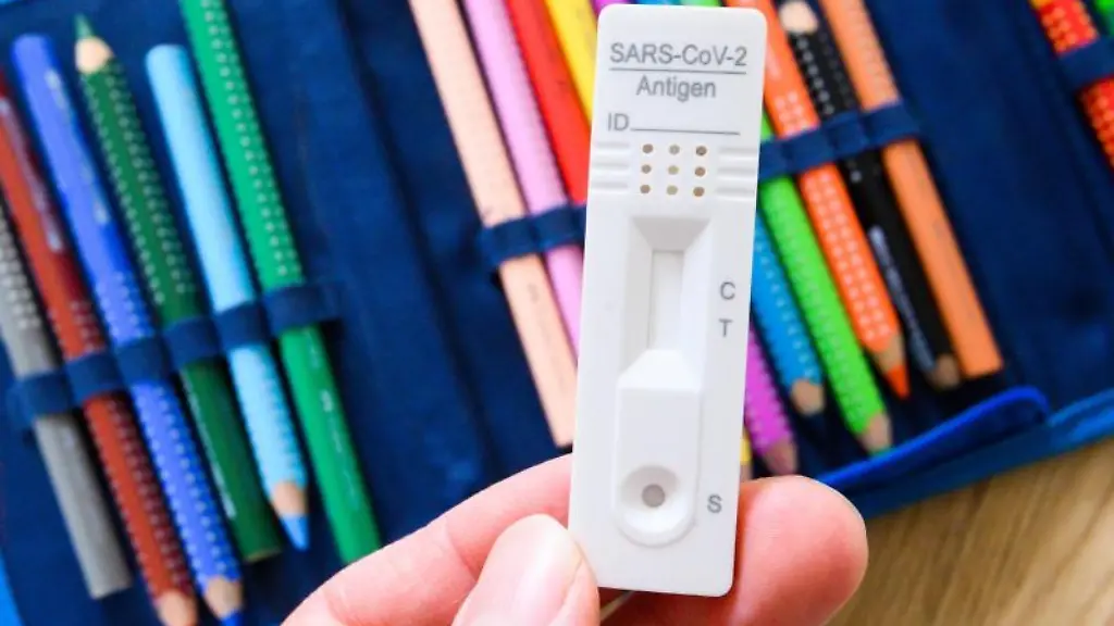 Ein-Corona-Selbsttest-wird-ueber-dem-Federmaeppchen-eines-Grundschuelers-gehalten