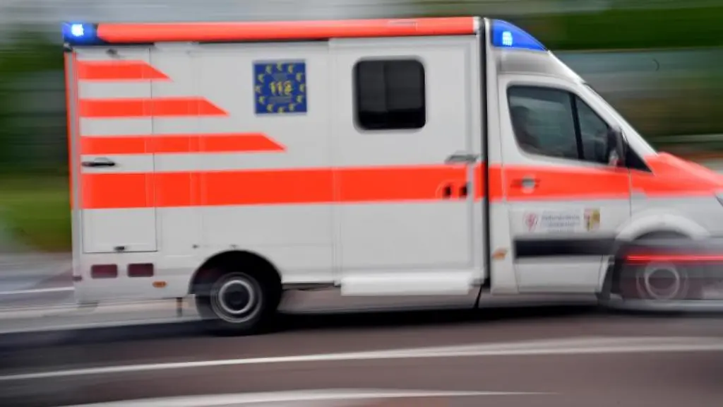 Ein-Krankenwagen-faehrt-mit-Blaulicht-auf-einer-Strasse