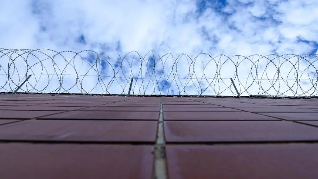 Stacheldrahtzaun-haengt-an-einer-Mauer-einer-Justizvollzugsanstalt