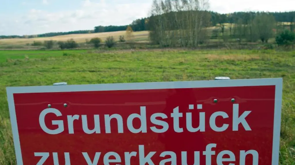 Ein-Schild-mit-der-Aufschrift-Grundstueck-zu-verkaufen-steht-an-einer-Strasse