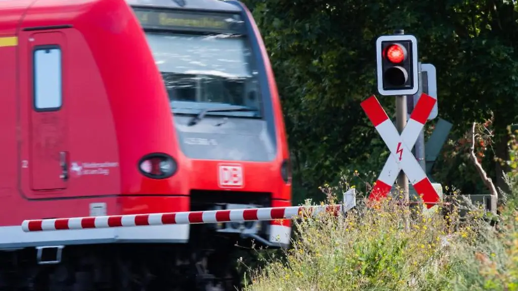 Eine-S-Bahn-der-Deutschen-Bahn-DB-faehrt-an-einem-Bahnuebergang-mit-einer-roten-Ampel-vorbei