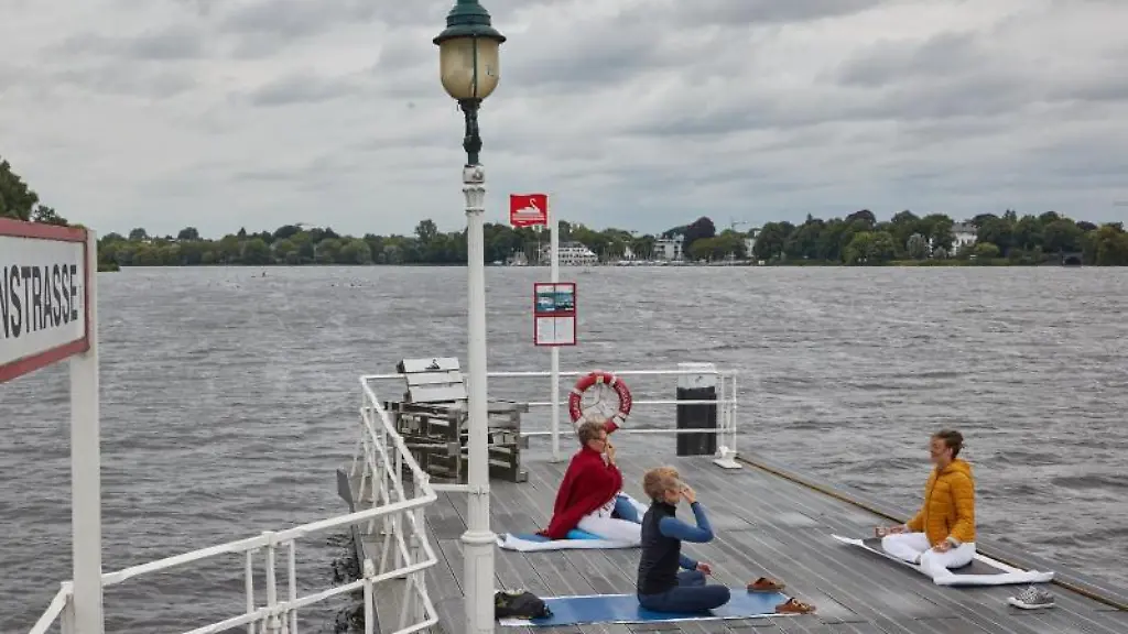 Drei-Frauen-praktizieren-Yoga-auf-dem-Bootsanleger-Rabenstrasse-an-der-Alster