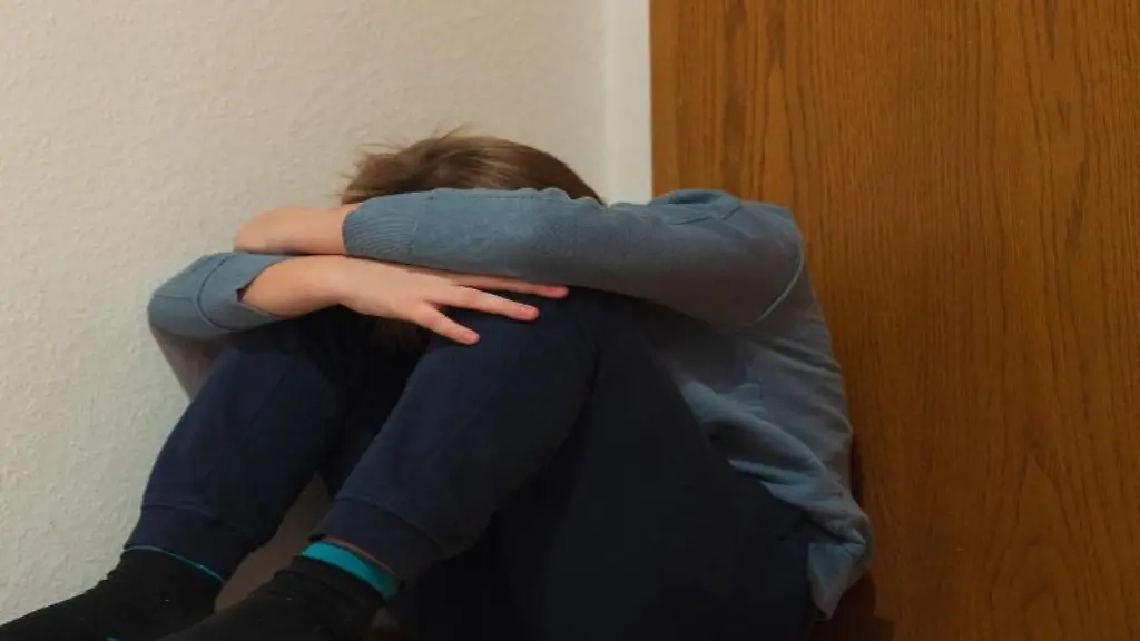 Ein-Junge-kauert-sich-in-der-Ecke-seines-Zimmers-am-Fussboden-sitzend-zusammen