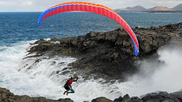 Der Extremsportler Mike Küng fliegt hier mit einem Gleitschirm an der Küste der spanischen Insel Lanzarote.