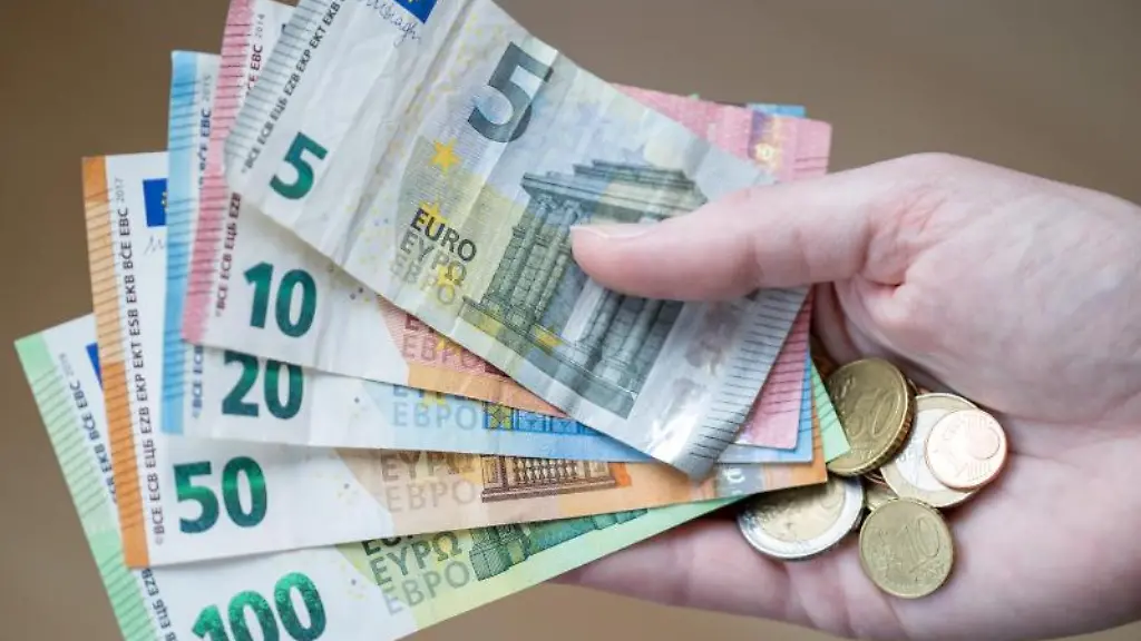 Eine-Frau-haelt-Geldscheine-und-Muenzen-in-der-Hand