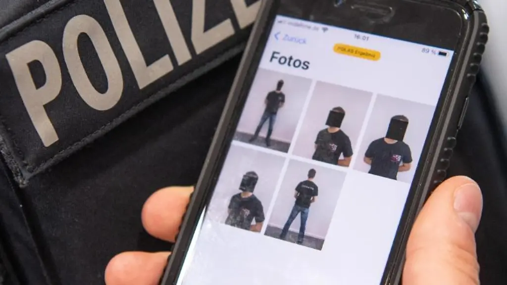 Ein-Polizist-zeigt-auf-seinem-Smartphone-eine-spezielle-Polizei-App