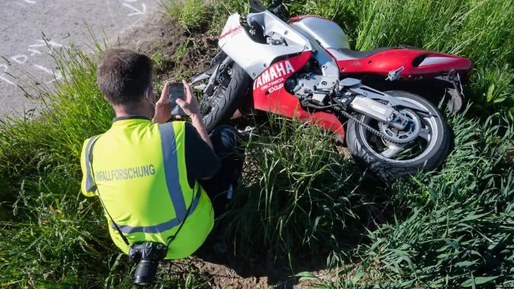 Ein-Mitarbeiter-der-Unfallforschung-hockt-vor-einem-verunfallten-Motorrad