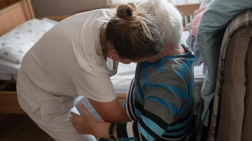 Eine-Pflegefachkraft-hilft-einer-Frau-beim-Umsetzen