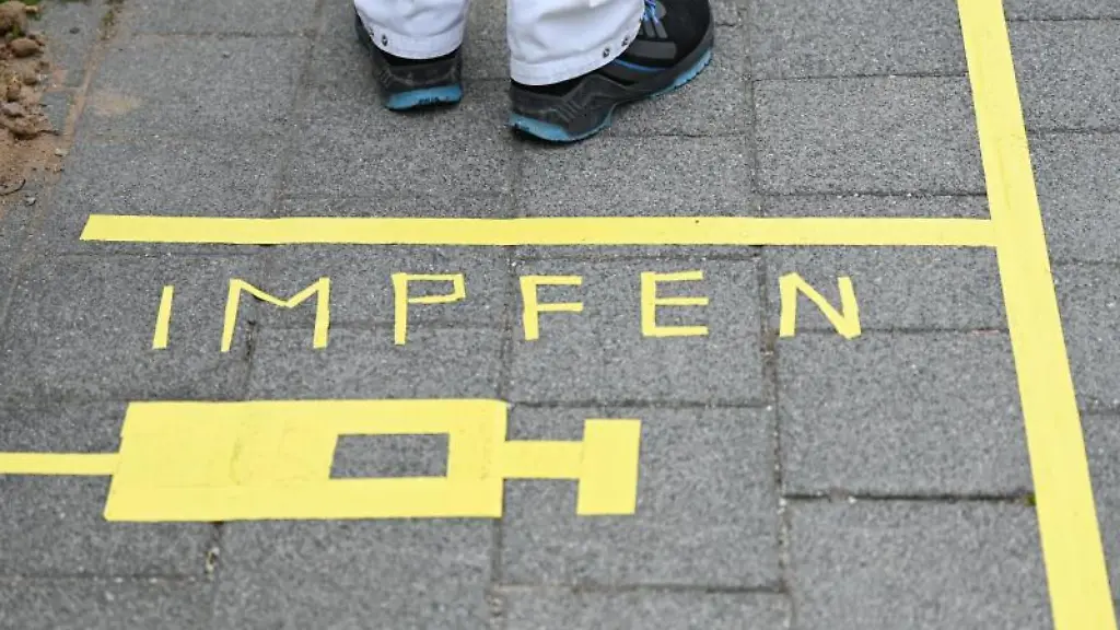 Ein-Mann-steht-an-einem-Covid-19-Impfcenter-hinter-der-Bodenaufschrift-Impfen
