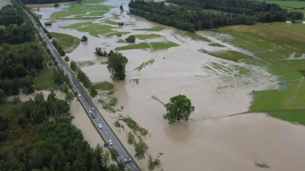 Die-Wiesen-links-und-rechts-einer-Strasse-vor-dem-Ort-sind-ueberschwemmt