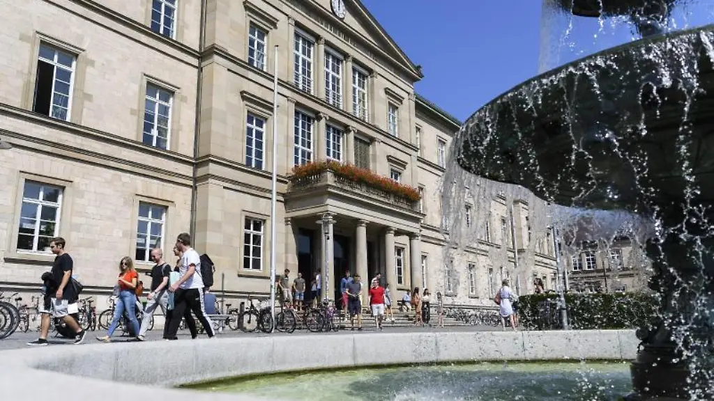 Studentinnen-und-Studenten-laufen-vor-der-Universitaet-Tuebingen-an-einem-Brunnen-vorbei